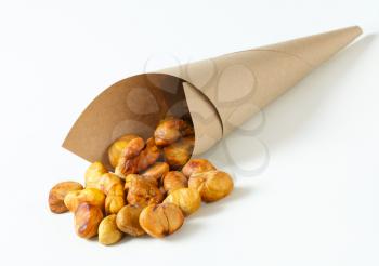 Peeled roasted chestnuts spill out of a paper cone