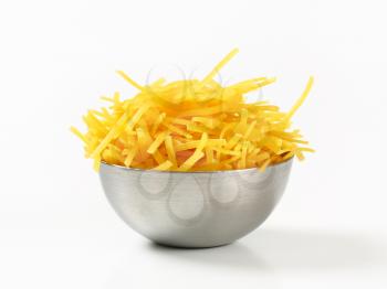 Dried egg noodles in metal bowl