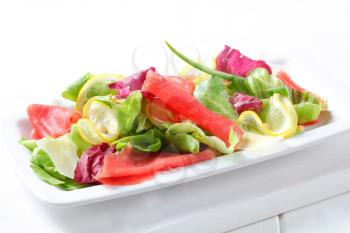 Green salad with thin slices of lemon and raw beef