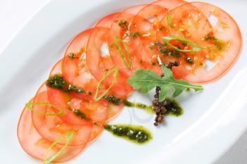 Thinly sliced tomato with pesto and spring onion
