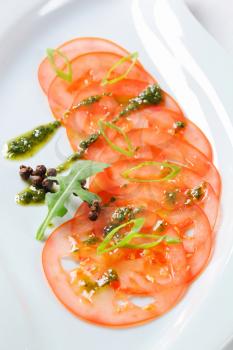 Thinly sliced tomato with pesto and spring onion