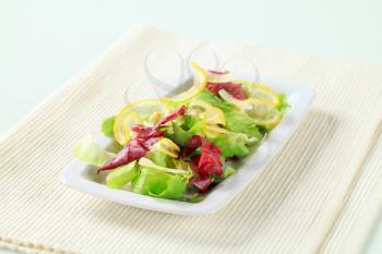 Green salad with slices of lemon, Parmesan shavings and pine nuts