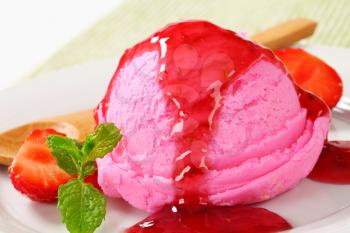 Scoop of pink ice cream with strawberry sauce