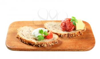 Slices of bread with cheese spread and salami