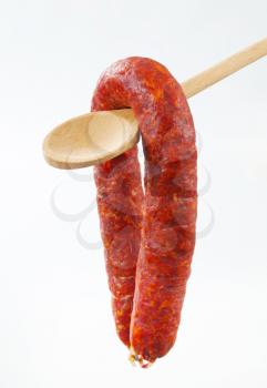 Spicy dry sausage on wooden spoon