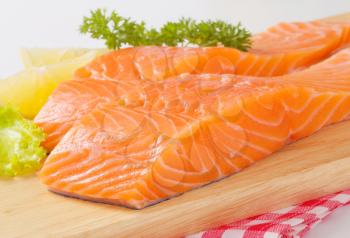Raw salmon fillets on cutting board