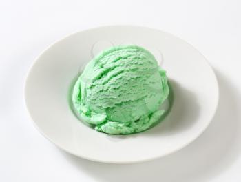 Scoop of green ice cream on plate