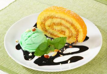 Slice of Swiss roll cake with green sherbet and chocolate sauce