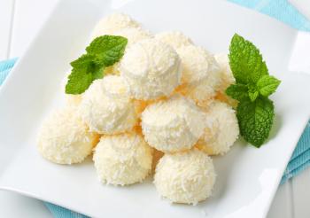 Pile of coconut snowball truffles on square plate