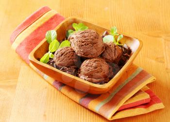 Scoops of chocolate ice cream and shavings in wooden bowl