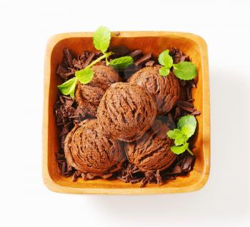 Scoops of chocolate ice cream and shavings in wooden bowl