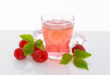 Glass of raspberry-flavored drink and fresh raspberries