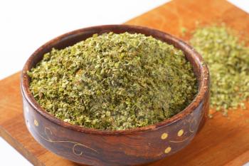 Heap of dried Marjoram leaves in a wooden bowl