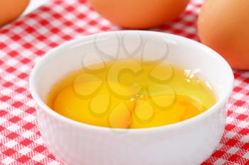 Fresh egg whites and yolks in white bowl