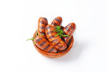 bowl of grilled sausages with parsley and rosemary