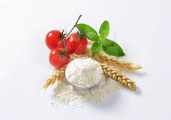 Bowl of finely ground flour, wheat ears and fresh tomatoes - still life