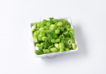 Chopped spring onions in square bowl