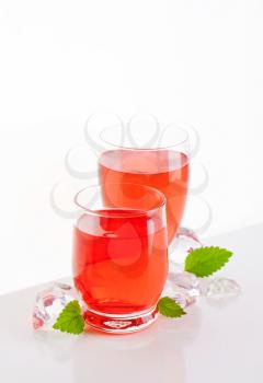 two glasses of fruit flavored drinks on white background