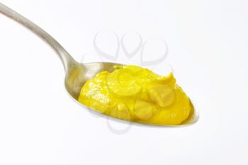 American yellow mustard on metal spoon
