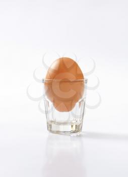 single brown egg in glass