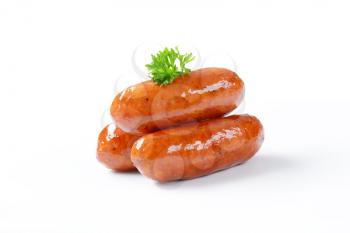 three pan fried sausages on white background