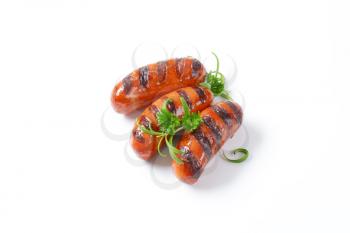 three grilled sausages on white background