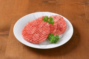 fresh hamburger patties on white plate