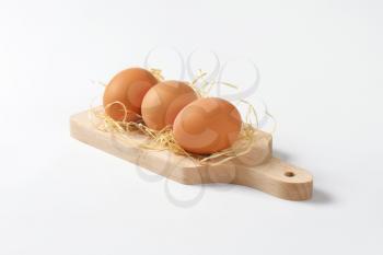fresh eggs on wooden cutting board