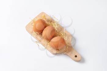 fresh eggs on wooden cutting board