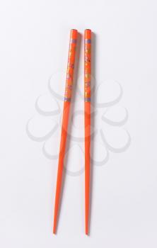 A pair of orange chopsticks with floral pattern