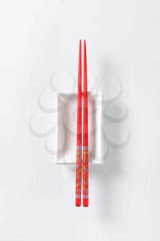 A pair of red chopsticks on empty soy sauce dish