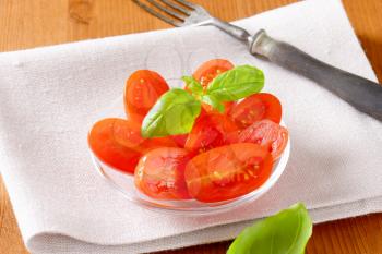 Halved fresh oval-shaped red tomatoes on glass plate