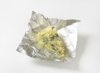 Wedge of French blue cheese on foil