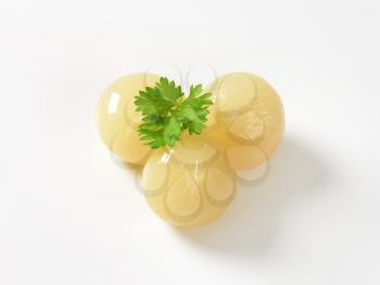 three small pickled onions on white background
