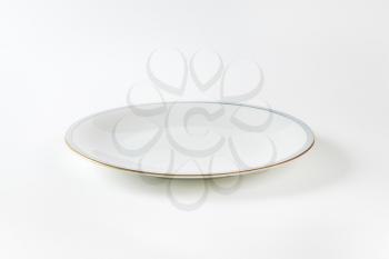 Coupe shaped white plate with blue band and gold trim