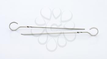 two metal skewers on off-white background