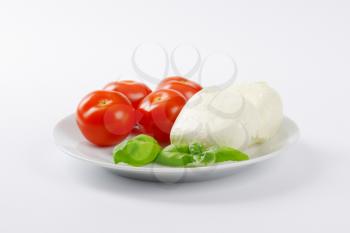 fresh mozzarella, basil and tomatoes - ingredients for caprese salad on white plate