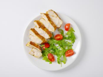 Slices of spice-rubbed chicken breast fillet with rocket leaves and cherry tomatoes