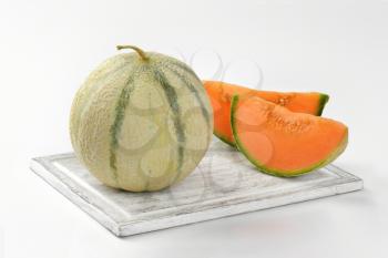 fresh cantaloupe melon on wooden cutting board