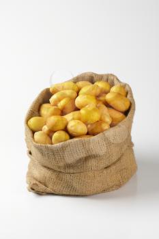 burlap sack of fresh potatoes on white background