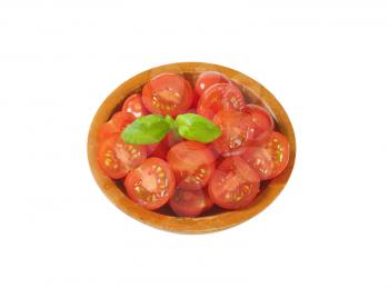 Halved cherry tomatoes in wooden bowl