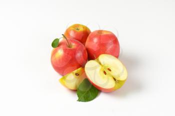 whole and cut apples with leaves on white background