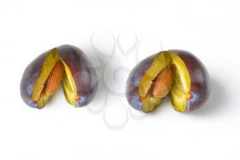 two halved ripe plums on white background
