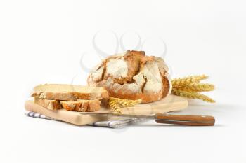 fresh bread - whole cob and slices - on wooden cutting board