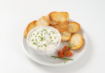slices of toasted baguette and bowl of chives cheese spread