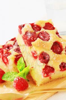 two pieces of homemade raspberry cake on a wooden cutting board