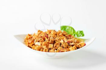 Granola with pieces of dried apples in a white bowl