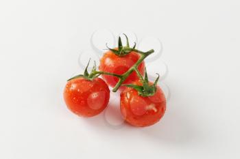 Three wet cherry tomatoes on vine
