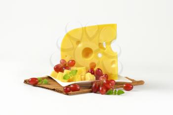 plate of Swiss cheese and red grapes on brown place mat