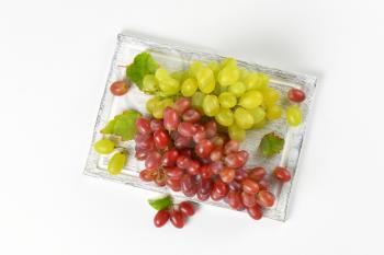 bunches of red and white grapes on wooden cutting board